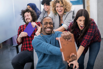 Image showing multiethnics business team racing on office chairs