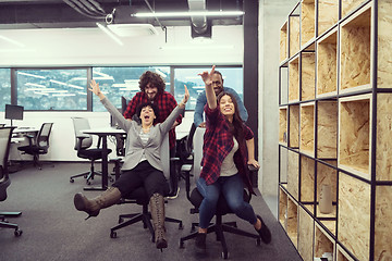 Image showing multiethnics business team racing on office chairs