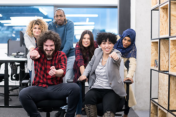 Image showing multiethnics business team racing on office chairs