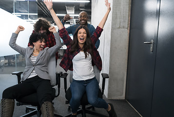 Image showing multiethnics business team racing on office chairs