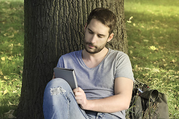 Image showing Young man reading e-book