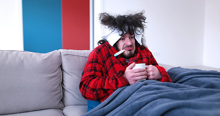 Image showing sick man is holding a cup while sitting on couch