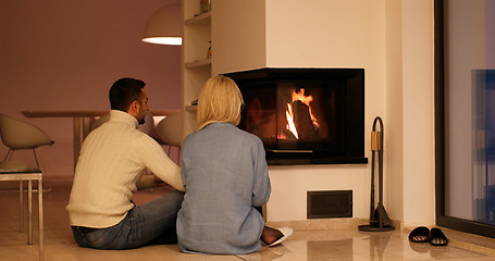 Image showing Young couple sitting in front of fireplace