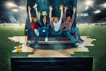 Image showing Soccer football fans sitting on the sofa and watching TV in the middle of a football field.