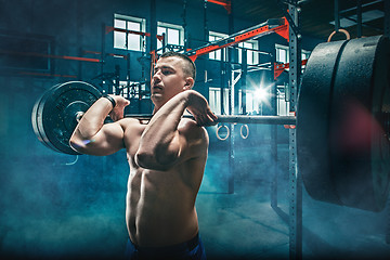 Image showing Fit young man lifting barbells working out in a gym