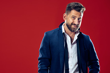 Image showing The happy business man standing and smiling against red background.