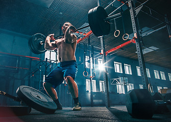 Image showing Fit young man lifting barbells working out in a gym