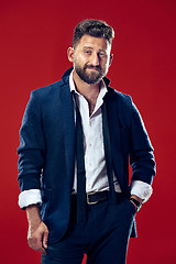 Image showing The happy business man standing and smiling against red background.