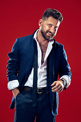 Image showing The happy business man standing and smiling against red background.