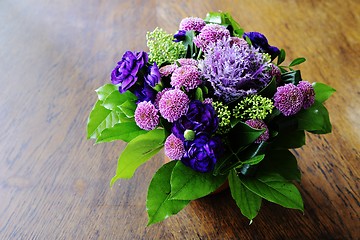 Image showing bouquet of flowers in a ceramic vase on a wooden table