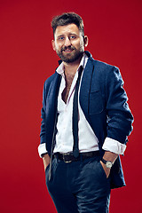 Image showing The happy business man standing and smiling against red background.