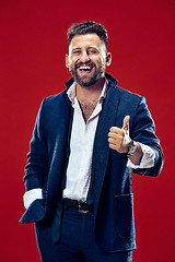 Image showing The happy business man standing and smiling against red background.