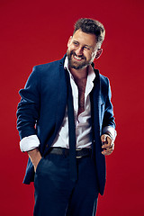Image showing The happy business man standing and smiling against red background.