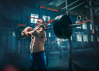 Image showing Fit young man lifting barbells working out in a gym