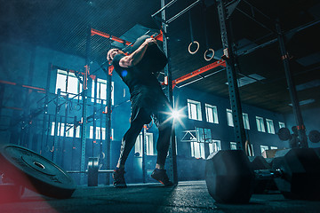 Image showing Fit young man lifting barbells working out in a gym