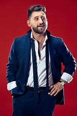 Image showing The happy business man standing and smiling against red background.