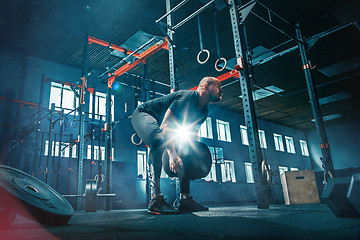 Image showing Fit young man lifting barbells working out in a gym