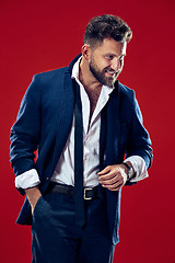 Image showing The happy business man standing and smiling against red background.