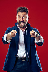 Image showing The happy business man point you and want you, half length closeup portrait on red background.