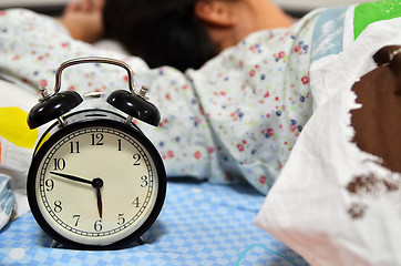 Image showing Pretty girl sleeping on the background of a retro alarm clock