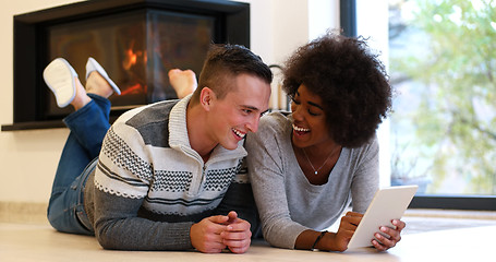 Image showing multiethnic couple using tablet computer on the floor