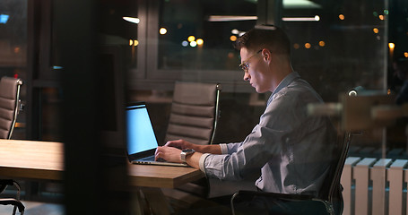 Image showing man working on laptop in dark office