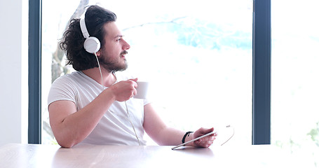 Image showing young man listenig music on tablet at home