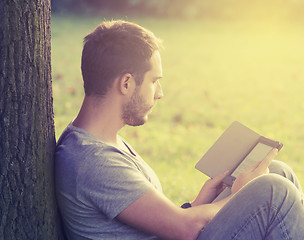 Image showing Young man reading e-book