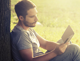 Image showing Young man reading e-book