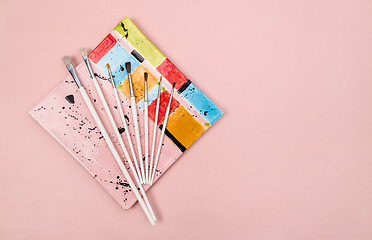 Image showing Colorful ceramic plate and paintbrushes on pink background