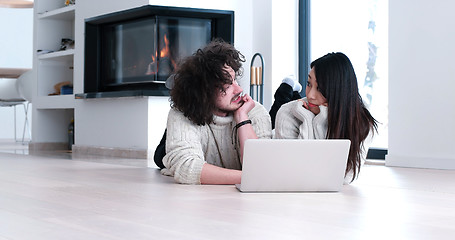 Image showing young multiethnic couple using a laptop on the floor