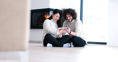 Image showing Young Couple using digital tablet on the floor