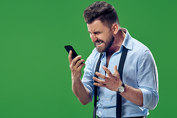 Image showing The young emotional angry man screaming on green studio background