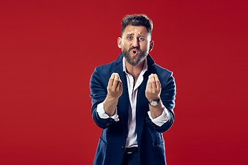 Image showing Beautiful male half-length portrait isolated on red studio backgroud. The young emotional surprised man