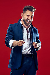 Image showing The happy business man point you and want you, half length closeup portrait on red background.