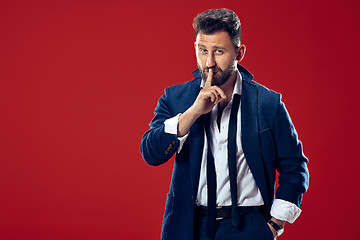 Image showing The young man whispering a secret behind her hand over red background