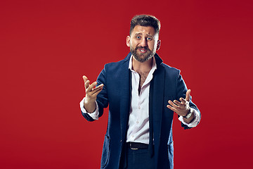 Image showing Beautiful male half-length portrait isolated on red studio backgroud. The young emotional surprised man