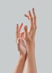 Image showing Beautiful woman hands with pastel manicured nails isolated on a gray background, copy space. Massage of hands using cream. Close up.