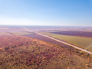 Image showing Panoramic landscape with endless farmlands, forests and highway in a autumn time on a background of clear sky. Aerial view from drone.