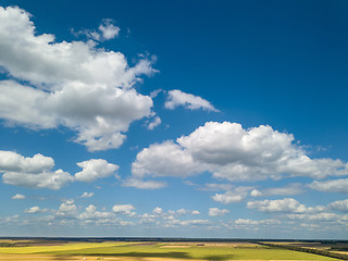 Image showing Landscape with beautiful white clouds and fields on a background of blue sky in a sunny day. Aerial view frome drone,