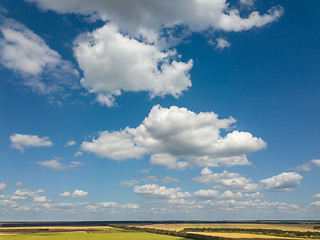 Image showing Panoramic landscape with beautiful white clouds and fields on a background of blue sky in a sunny day. Aerial view frome drone,