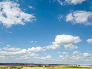 Image showing Cloudy aerial landscape with white clouds and fields on a blue sky background. Aerial view from drone.