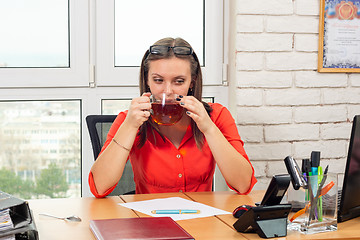 Image showing An office employee drinks tea at the workplace at lunchtime