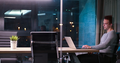 Image showing man working on laptop in dark office