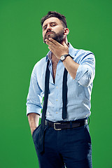 Image showing Male beauty concept. Portrait of a fashionable young man with stylish haircut wearing trendy suit posing over red background.