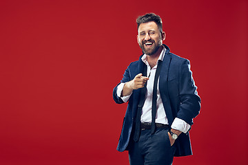 Image showing The happy business man point you and want you, half length closeup portrait on red background.