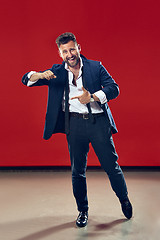 Image showing The happy business man pointing to left, half length closeup portrait on red background.