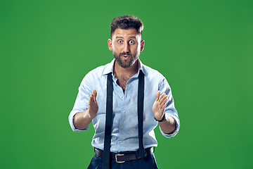 Image showing The young attractive man looking suprised isolated on green