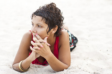 Image showing Attractive brunet woman in red lying on a sand.