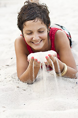 Image showing Attractive brunet woman in red lying on a sand.